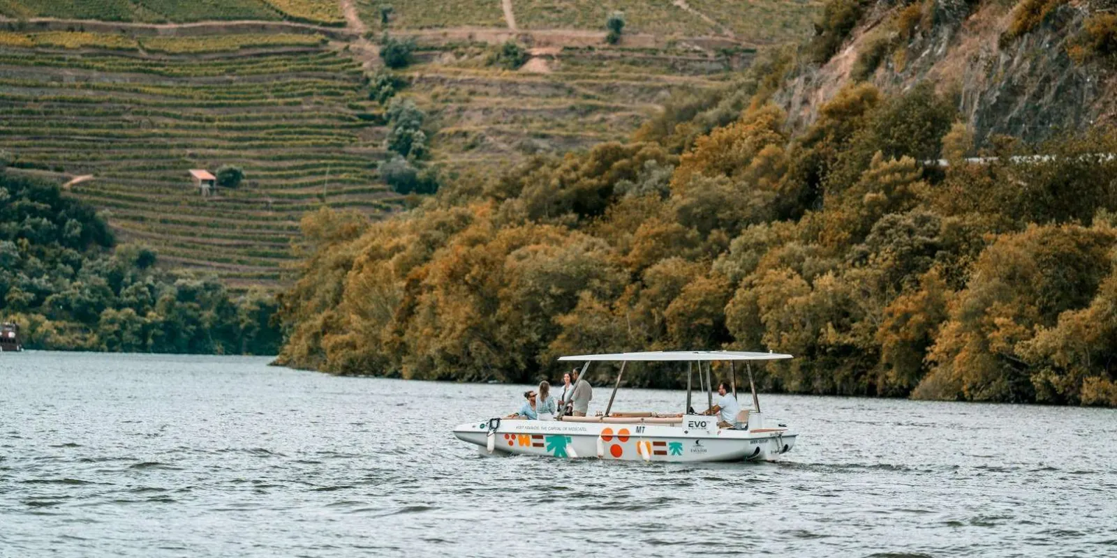 Passengers relaxing on deck as the solar boat cruises past vineyard-covered hills