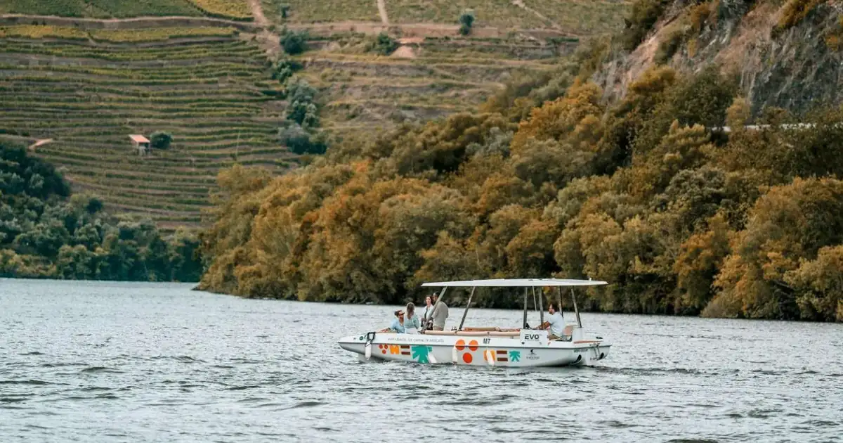 A solar-powered boat on the Douro River below terraced vineyards near Pinhão